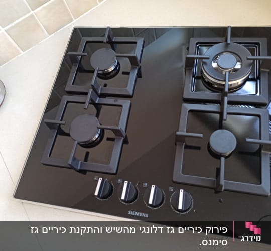 כיריים גז שחורות עם ארבעה מבערים וכפתורי שליטה